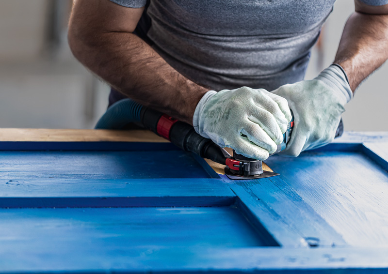 Detailbild, abschleifen, exzenterschleifer, blaues oberflächenmaterial, schutzhandschuhe, baumaschine