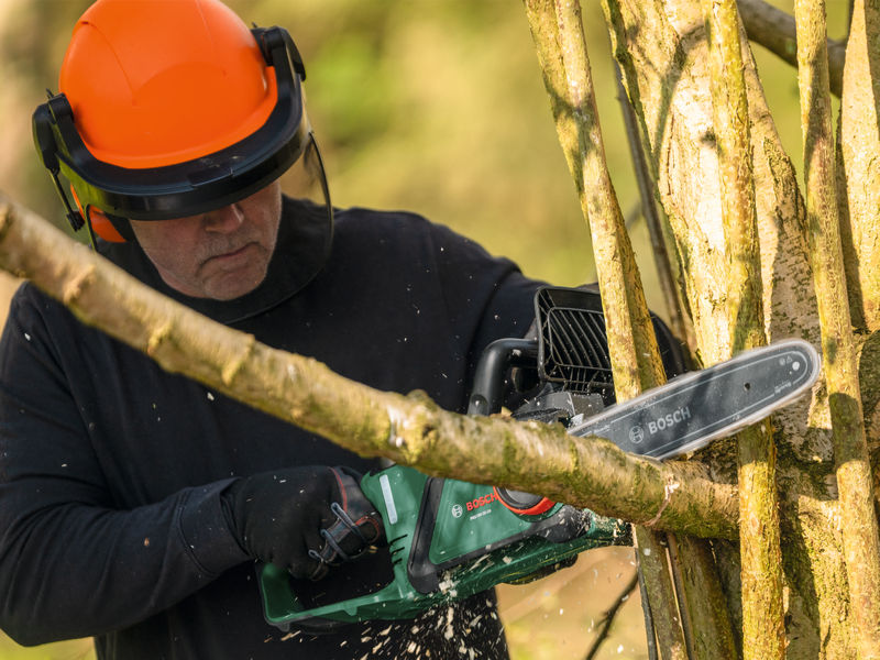 Anwendungsbild, Kettensäge, Säge, Holzbearbeitung, Schnitt, Arbeiter mit Schutzhelm